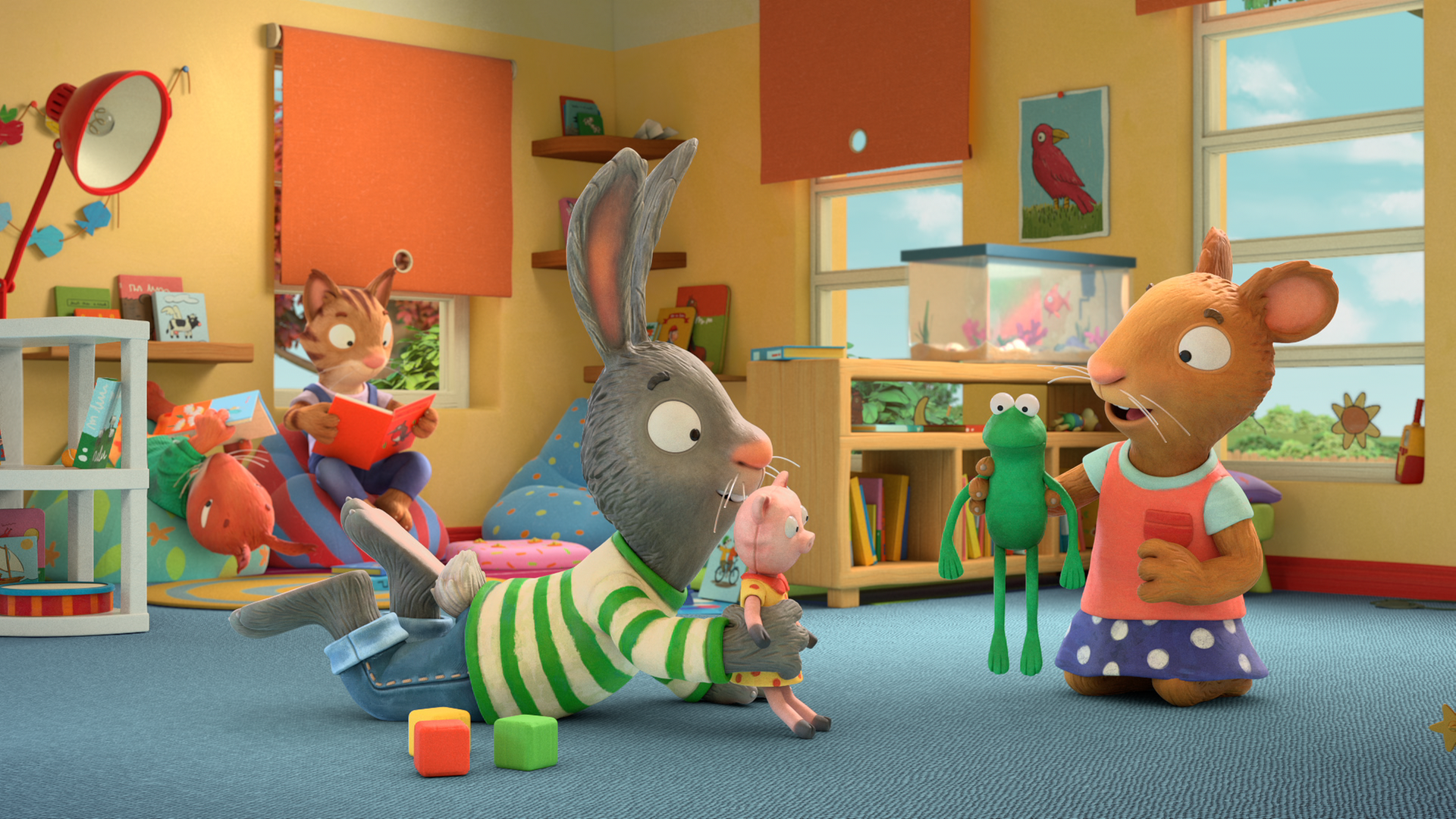 Pip liegt auf dem Bauch und hält Schweinchen in der Hand. Posy kniet und hebt Froschi hoch. Die beiden spielen mit den Kuscheltieren. Im Hintergrund sitzen Frankie und Jamila auf Sitzsäcken und lesen.