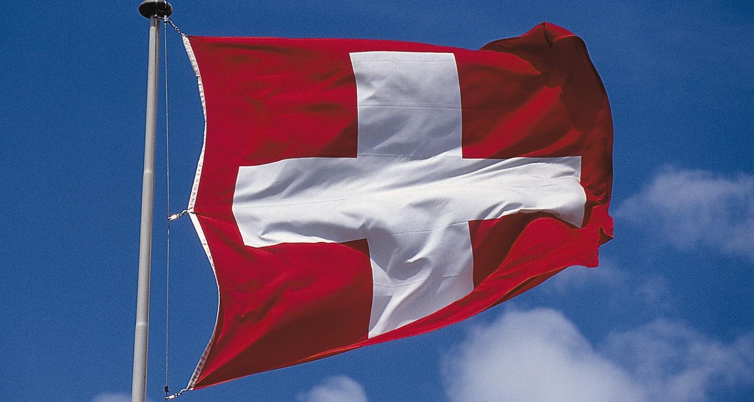 Schweizer Flagge vor blauem Himmel im Wind