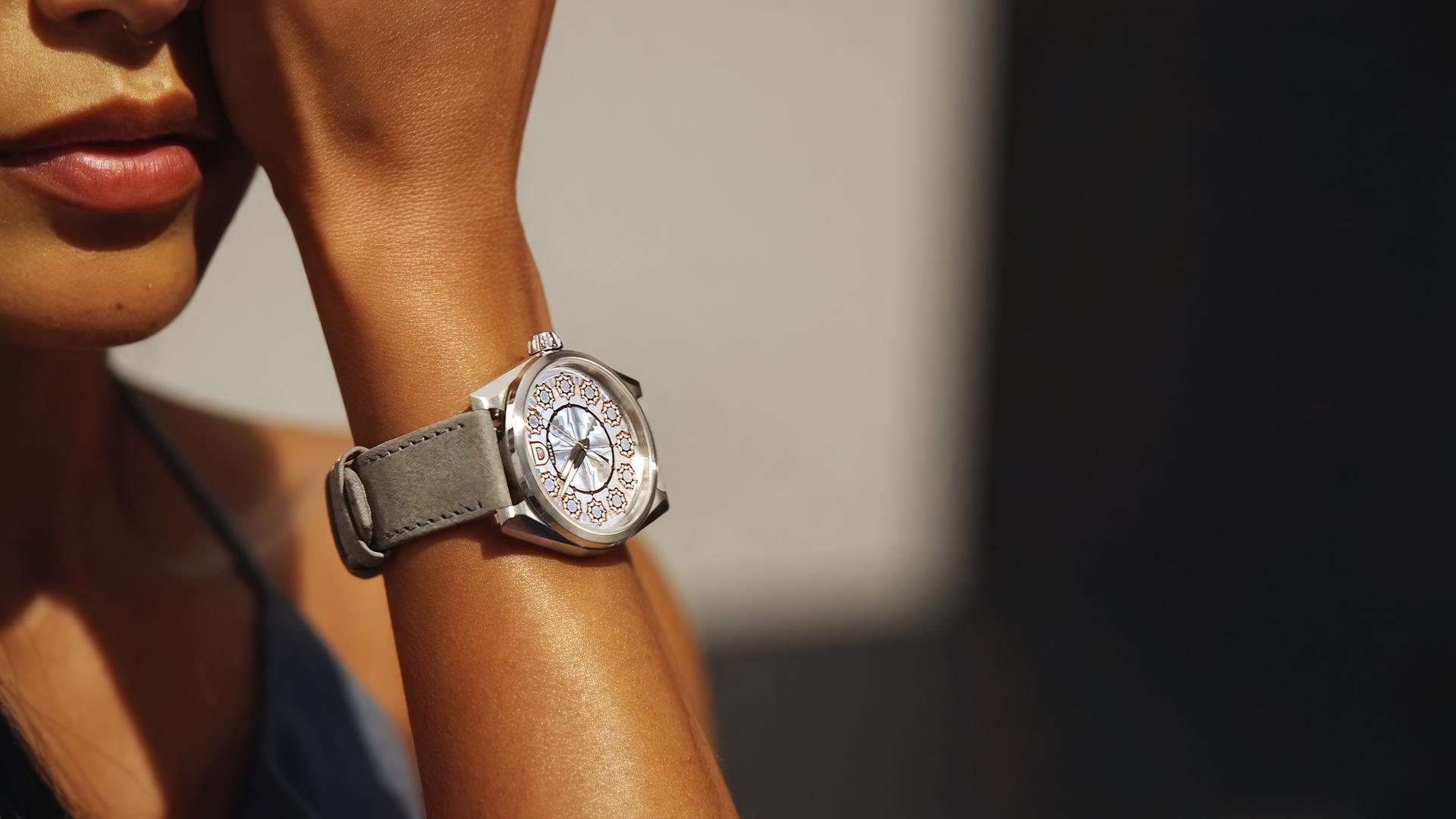 Eine Armbanduhr am gebräunten Arm einer Frau