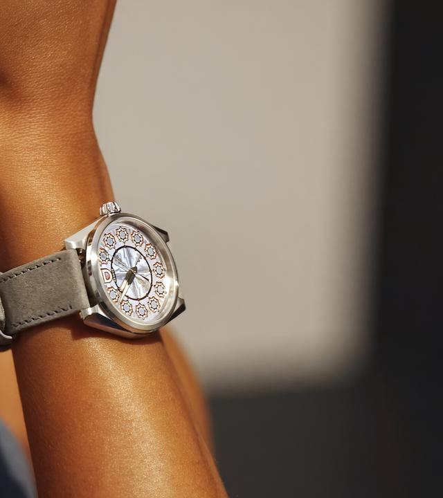 Eine Armbanduhr am gebräunten Arm einer Frau