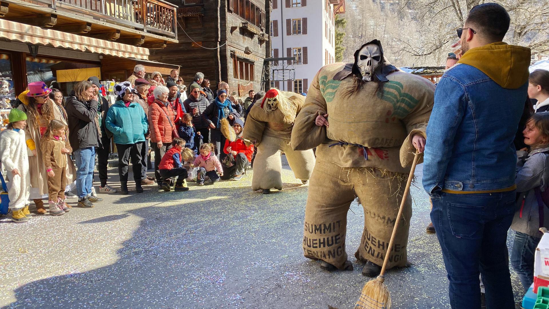 Carnaval d'Evolène, Umzug der Strohmänner. Am letzten Sonntag des Karnevals erwachen Strohriesen zum Leben, die im Dorf ihr Unwesen treiben.