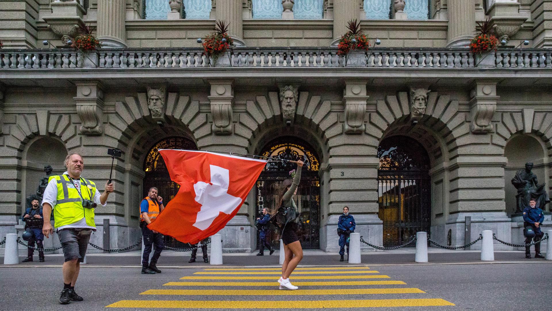 Eine Frau geht über die Straße mit einer Schweizer Fahne in der Hand.