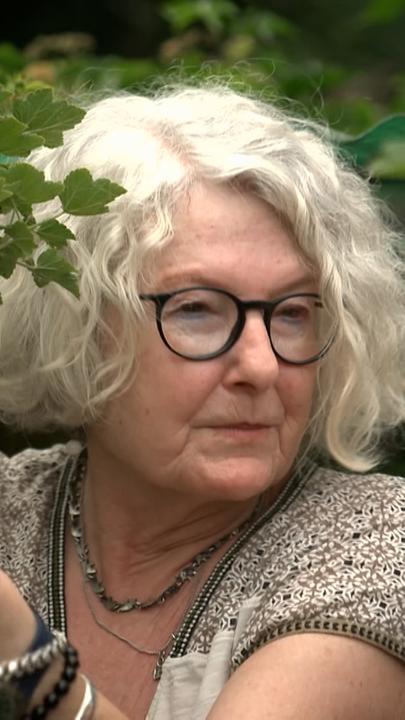 Eine Schweizer Klimaseniorin pflückt Beeren von einem Strauch