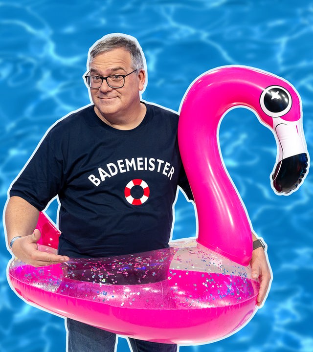 Elton trägt einen Schwimmreif in Form eines Flamingos.