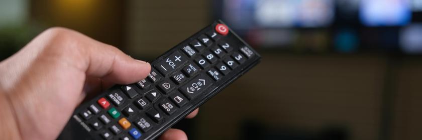 Eine Fernbedienung wird auf einen Fernseher gerichtet.