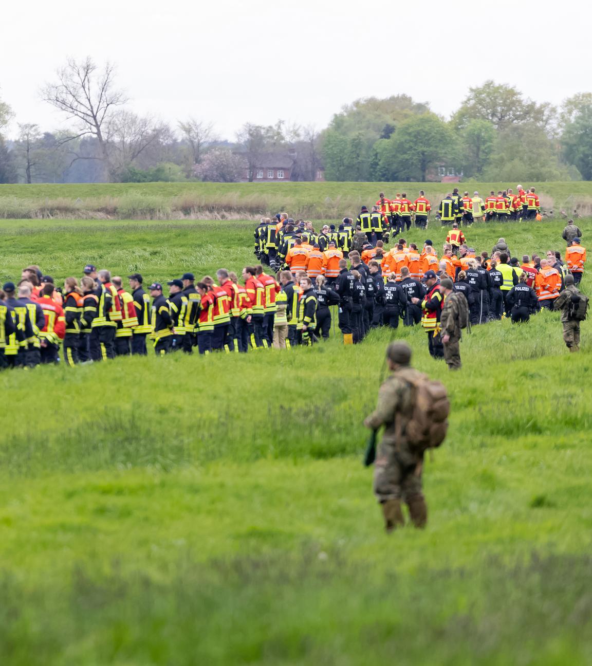 Niedersachsen, Gräpel: Soldaten der Bundeswehr und Einsatzkräfte von Feuerwehr und Polizei stellen sich auf, um ein Feld abzusuchen. 