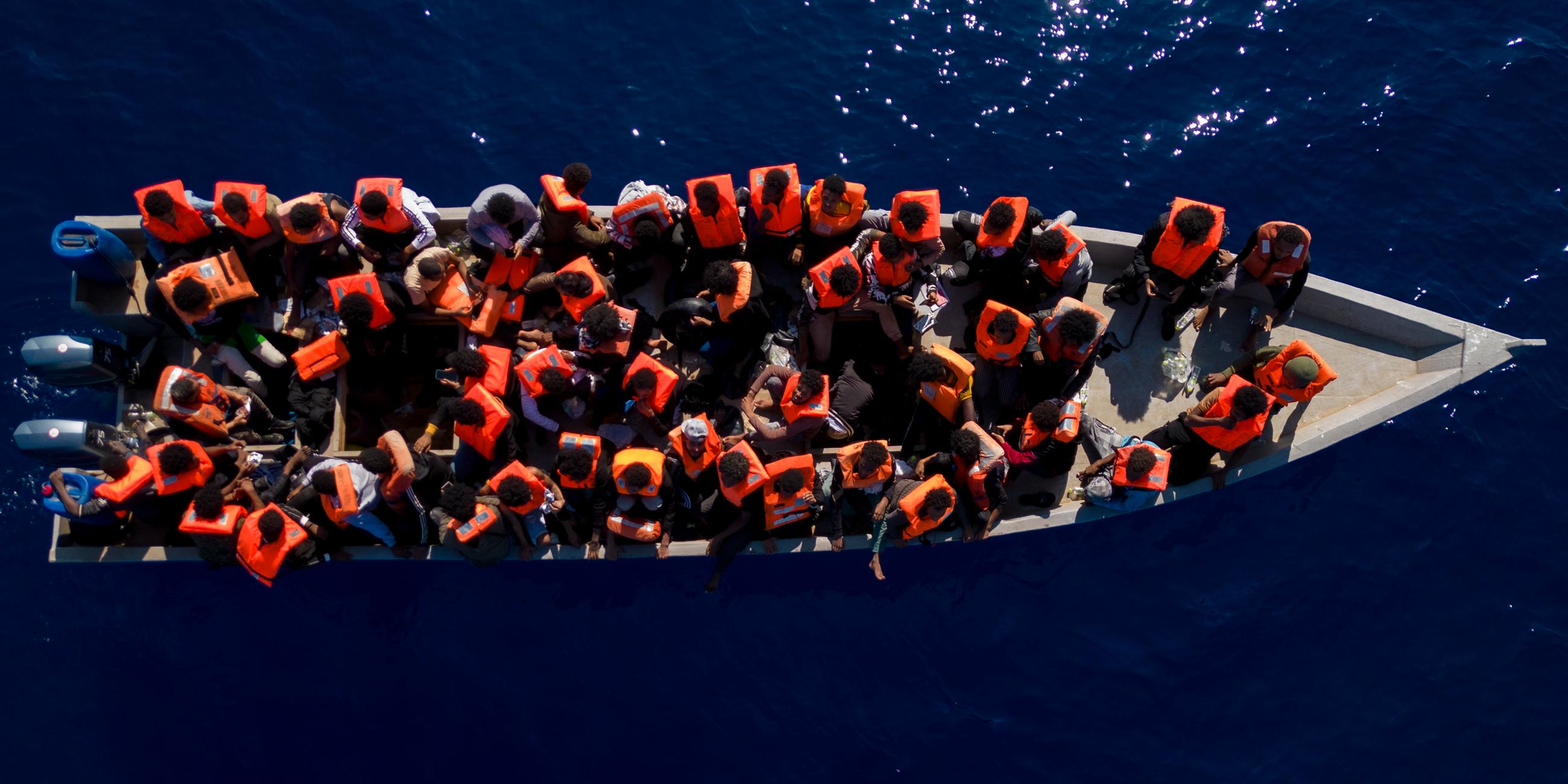 Migranten aus Eritrea, Libyen und dem Sudan sitzen in einem Holzboot, bevor sie von Helfern der spanischen Nichtregierungsorganisation Open Arms im Mittelmeer.