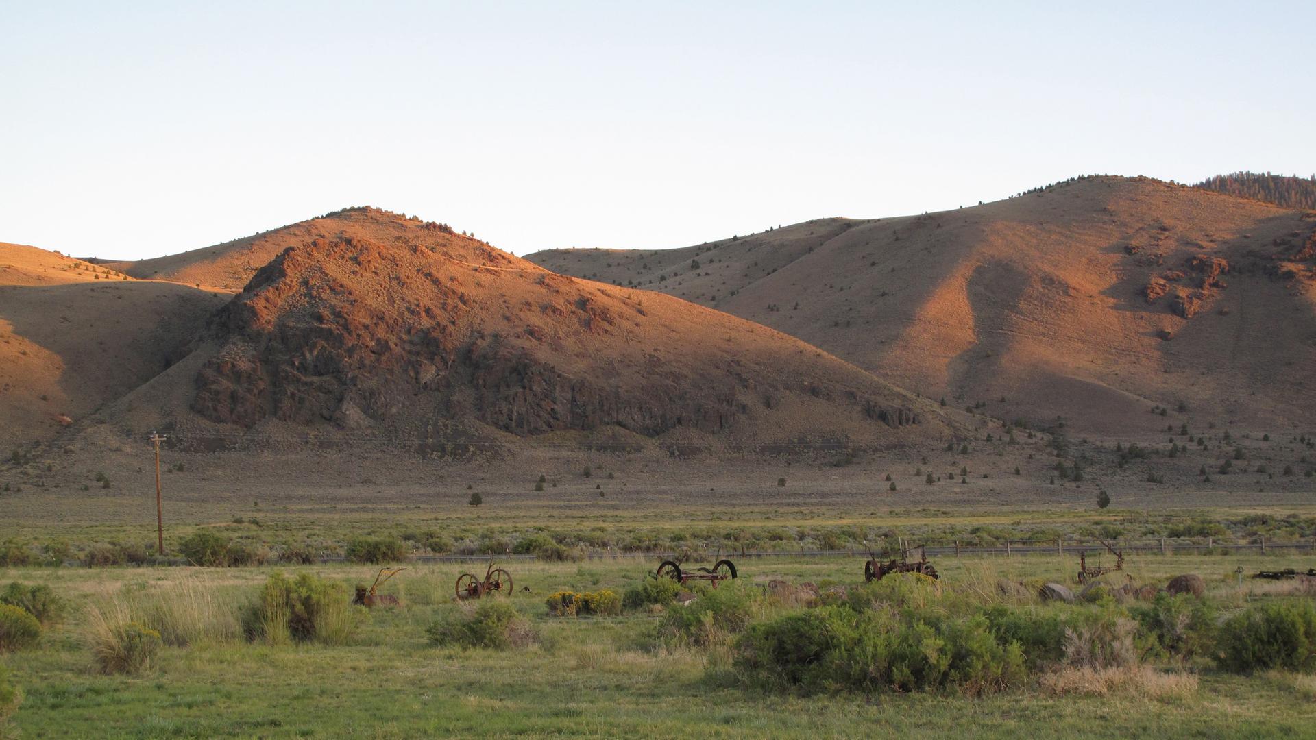"Die Entstehung der Erde - Amerikas Eiszeit": Im Vordergrund befindet sich eine grüne Wiese. Die Berghügel im Hintergrund werden von der Sonne beleuchtet.
