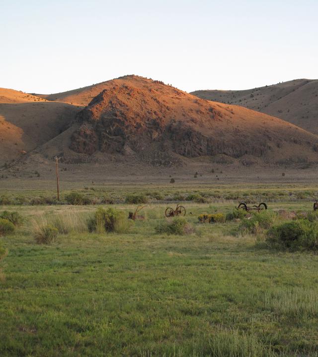 "Die Entstehung der Erde - Amerikas Eiszeit": Im Vordergrund befindet sich eine grüne Wiese. Die Berghügel im Hintergrund werden von der Sonne beleuchtet.