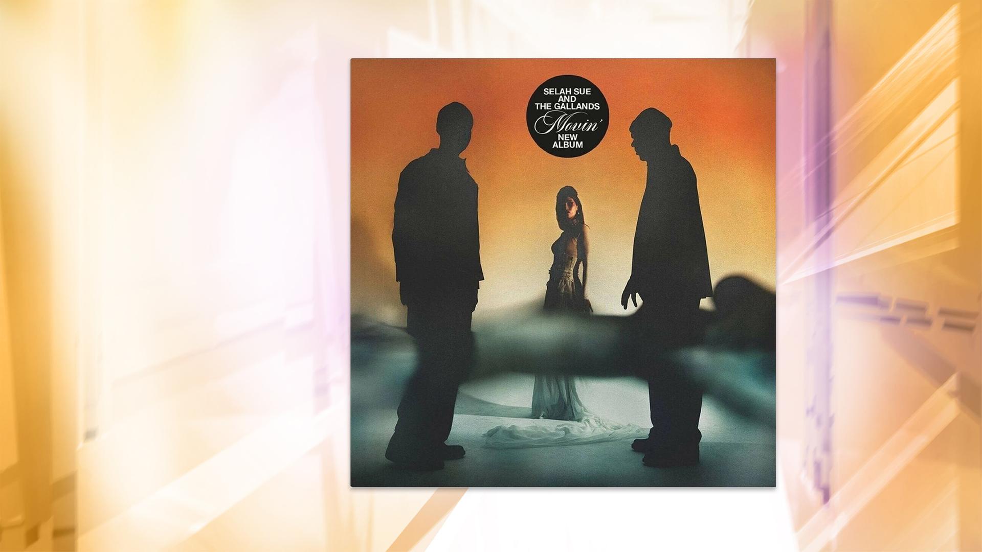 Eine Frau steht im Hintergrund, zwei Männer stehen im Gegenlicht vor ihr.