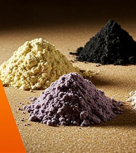 Seltene Erden liegen in unterschiedlichen Farben zu mehreren Häufchen auf Tischplatte