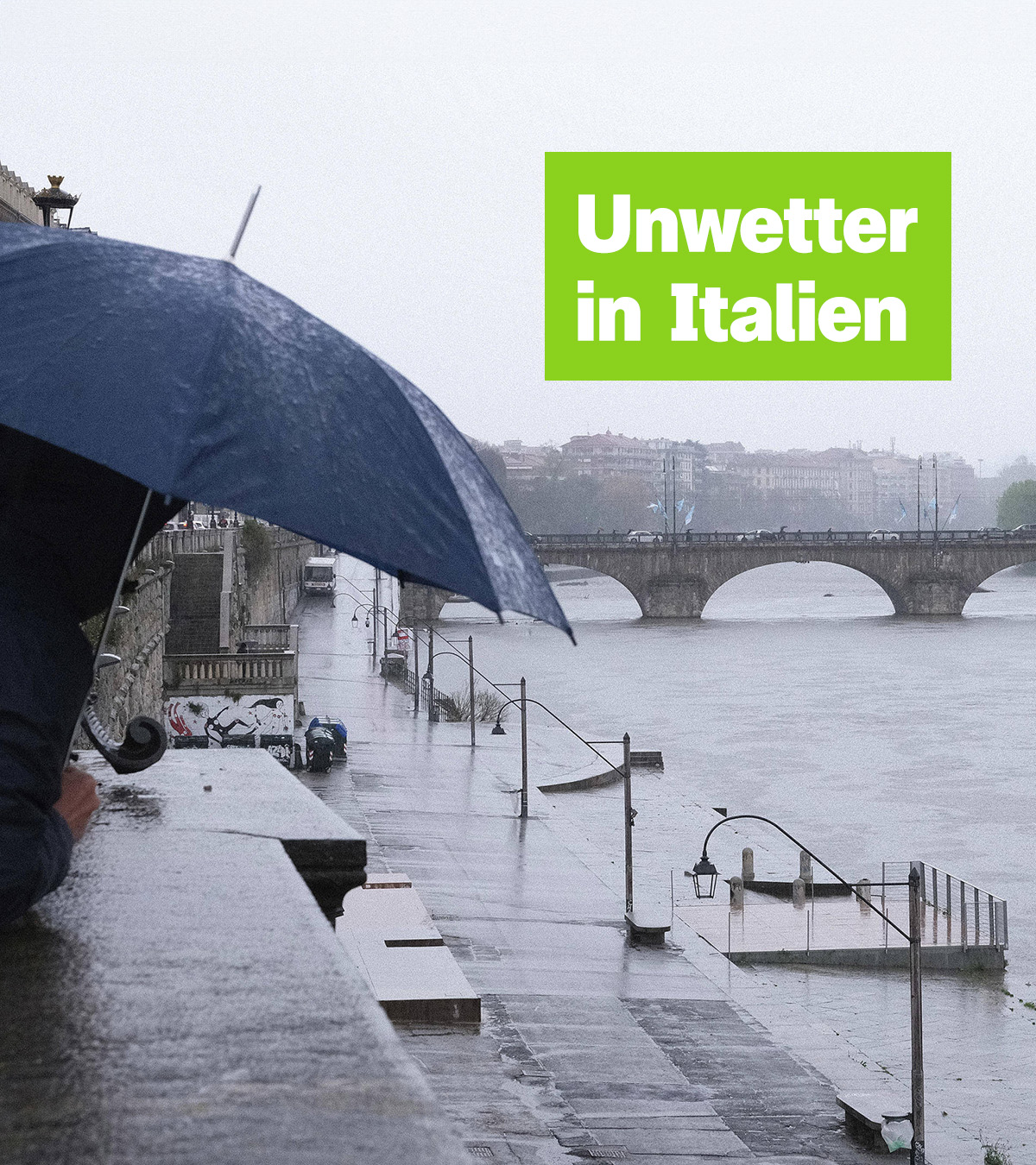Eine Person steht mit Regenschirm an einer verregneten Flusspromenade. Darüber der Schriftzug: "Unwetter in Italien".