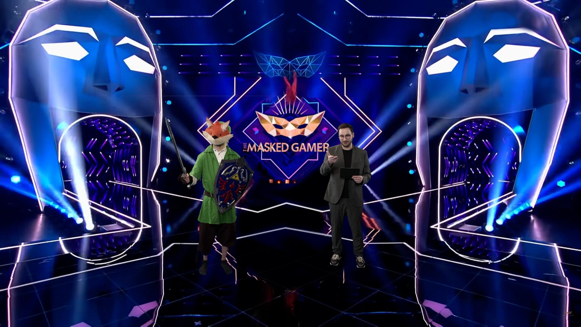 Zwei junge Männer stehen auf einer Showbühne. Der linke trägt eine Fuchsmaske.