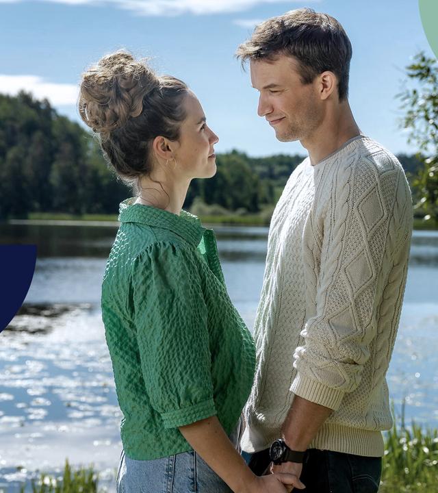 Ein junger Mann und eine junge Frau halten sich an den Händen und sehen sich glücklich und tief gegenseitig in die Augen.