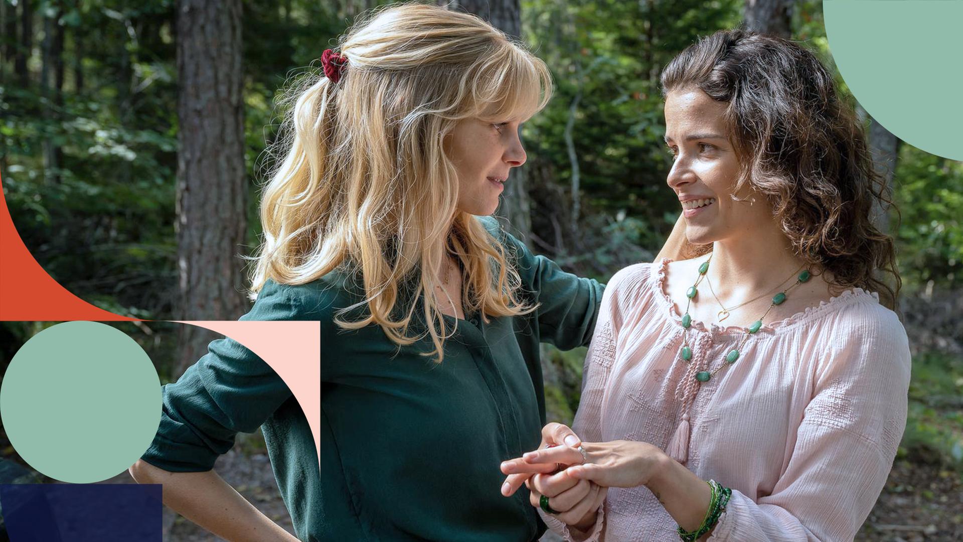 Liv (links) unterhält sich mit ihrer Schwester Smilla (rechts), die nervös mit dem Ring an ihrer Hand spielt. Im Hintergrund ist ein Wald zu sehen.