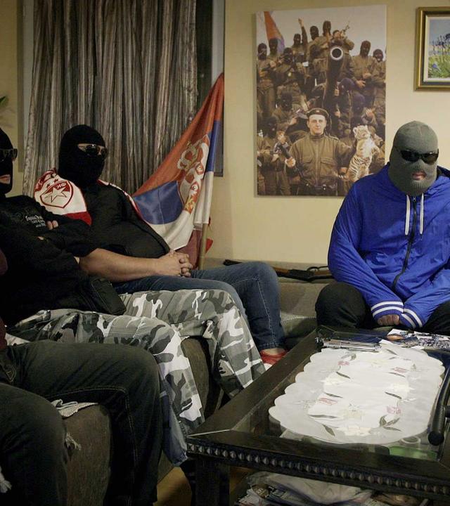 "Serbiens Mafia - Krieger, Kriminelle und der Staat": Der französische Journalist und Schriftsteller Jérôme Pierrat sitzt mit vermummten Hooligans am Tisch.