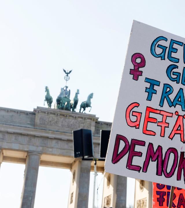 Neben einem steinernen Tor sieht man ein Demoplakat.