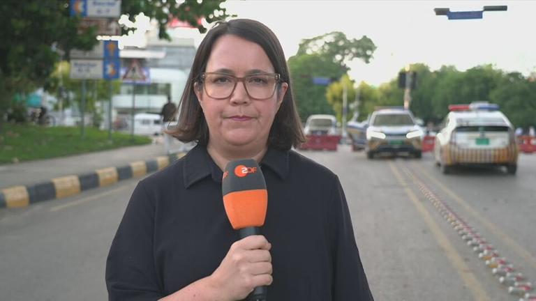 ZDF-Korrespondentin Gaa hält ein Mikrofon, im Hintergrund ist der Straßenverkehr von Islamabad zu sehen.