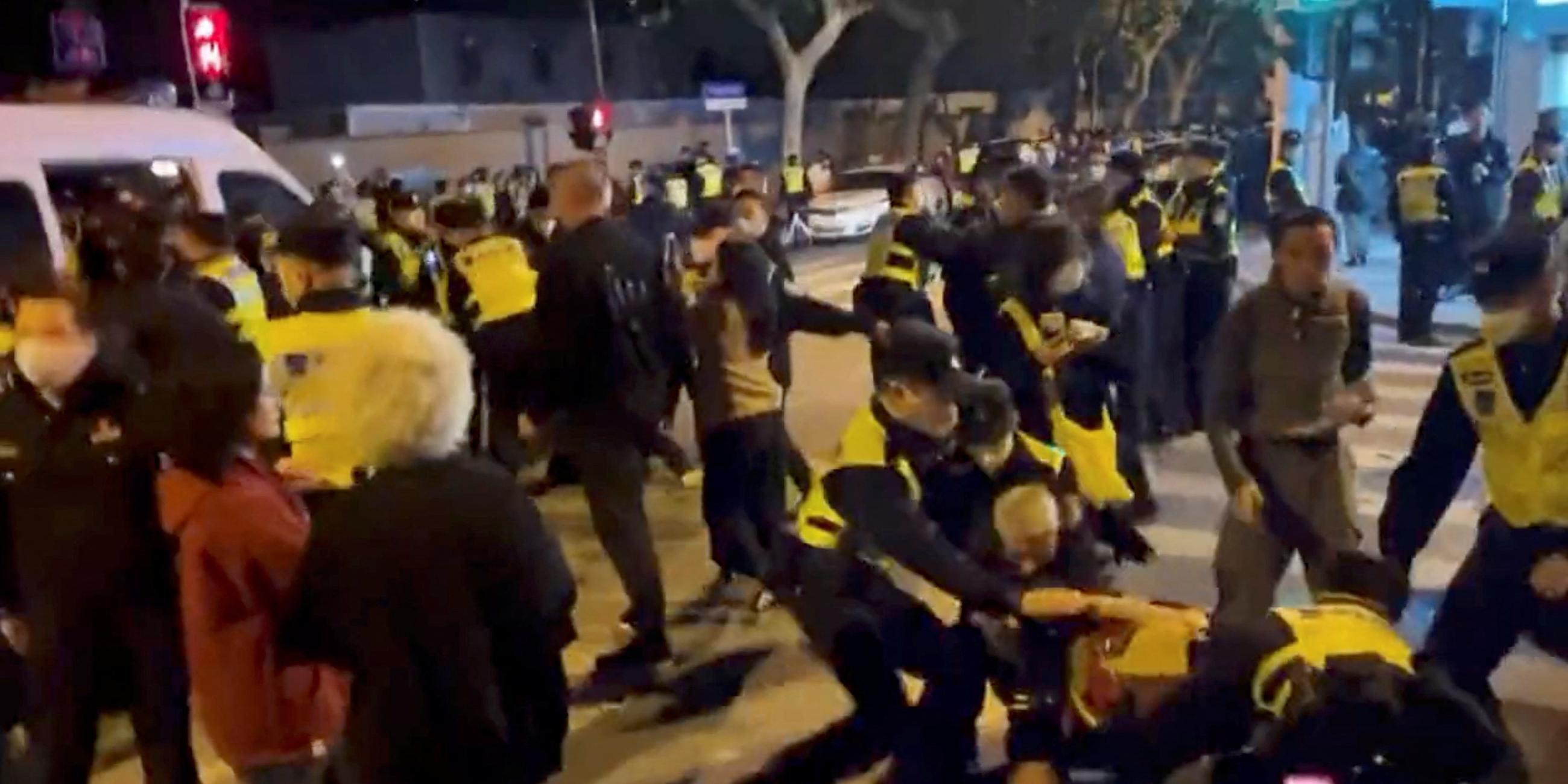 Police officers detain people during a protest against coronavirus disease (COVID-19) curbs at the site of a candlelight vigil for victims of the Urumqi fire, in Shanghai, China in this screengrab obtained from a video released on November 27, 2022.
