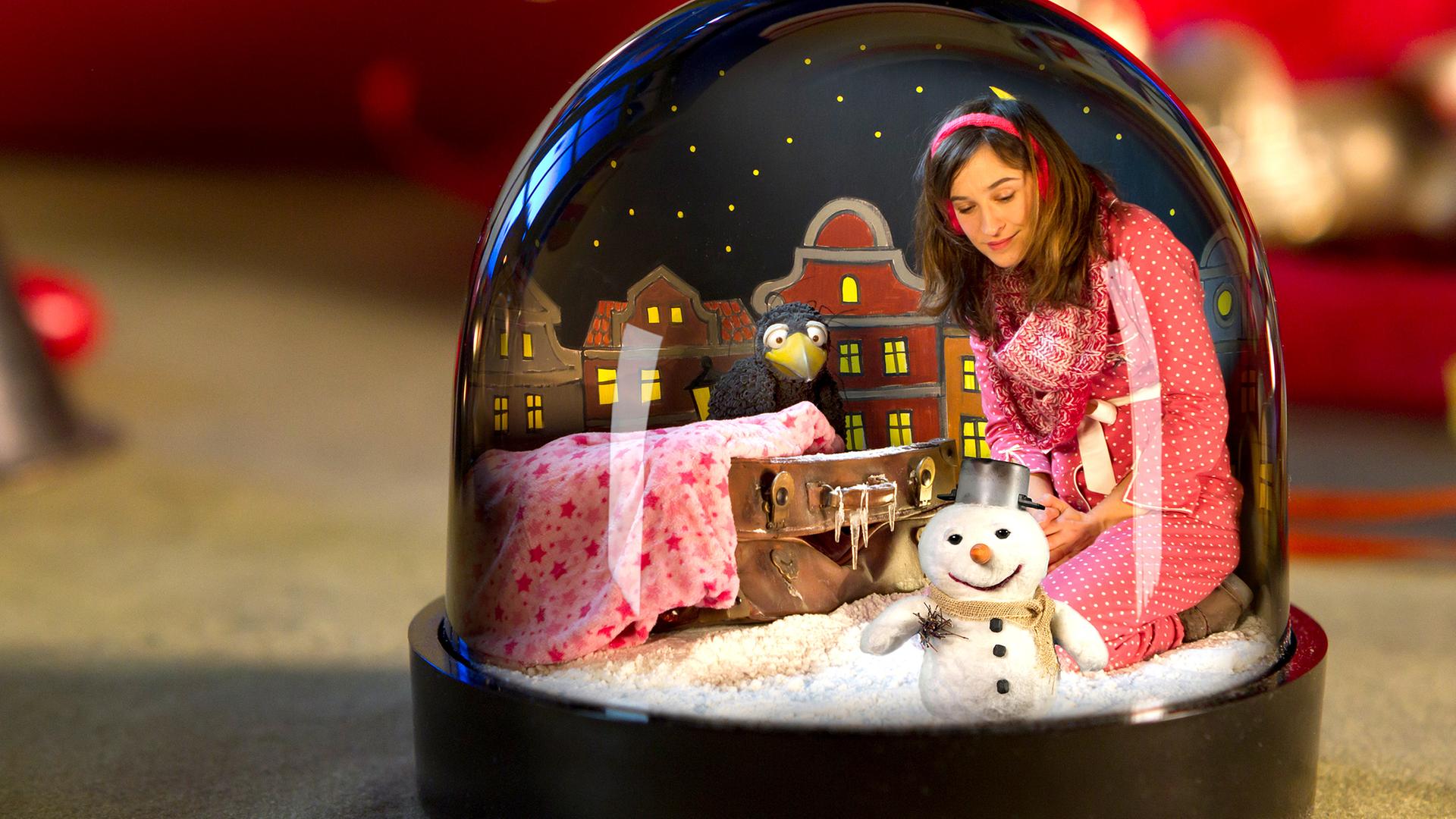 Rudi, Koffer, Schneemann und Frau Siebenstein sitzen in einer Schneekugel