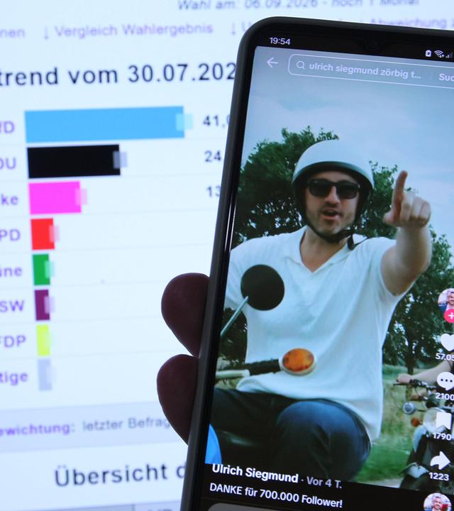 Eine Hand hält ein Smartphone, auf dem eine TikTok-Seite zu sehen ist, die einen Mann mit Helm und Sonnenbrille auf einem Moped zeigt.