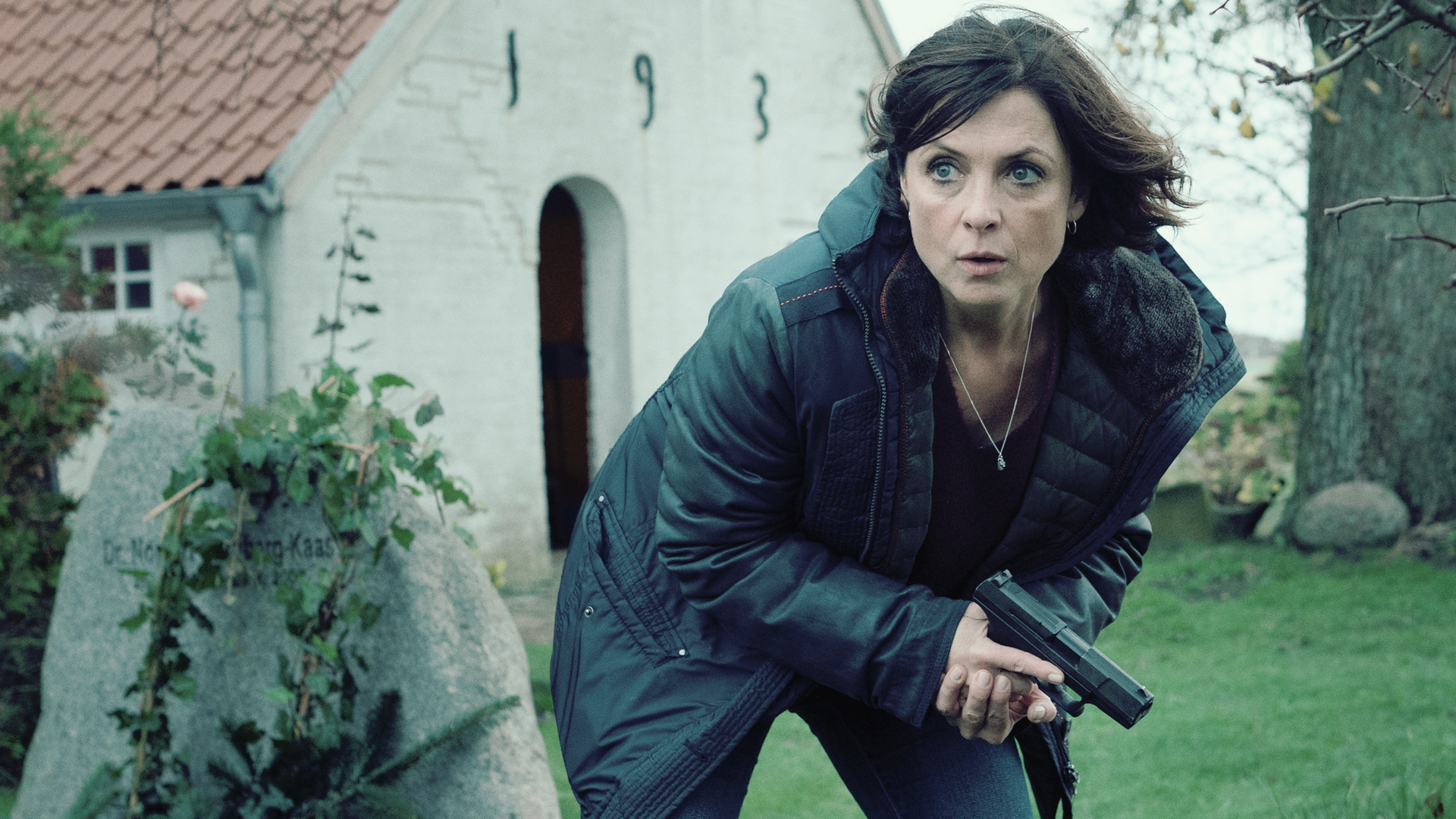 Ina Behrendsen (Julia Brendler) kauert auf einem Friedhof, ihre Waffe in der Hand. 