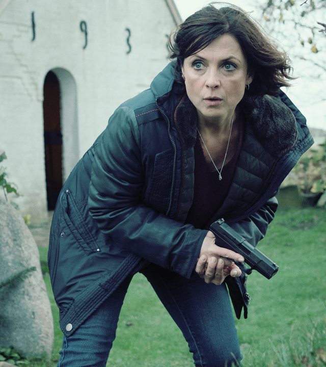 Ina Behrendsen (Julia Brendler) kauert auf einem Friedhof, ihre Waffe in der Hand. 