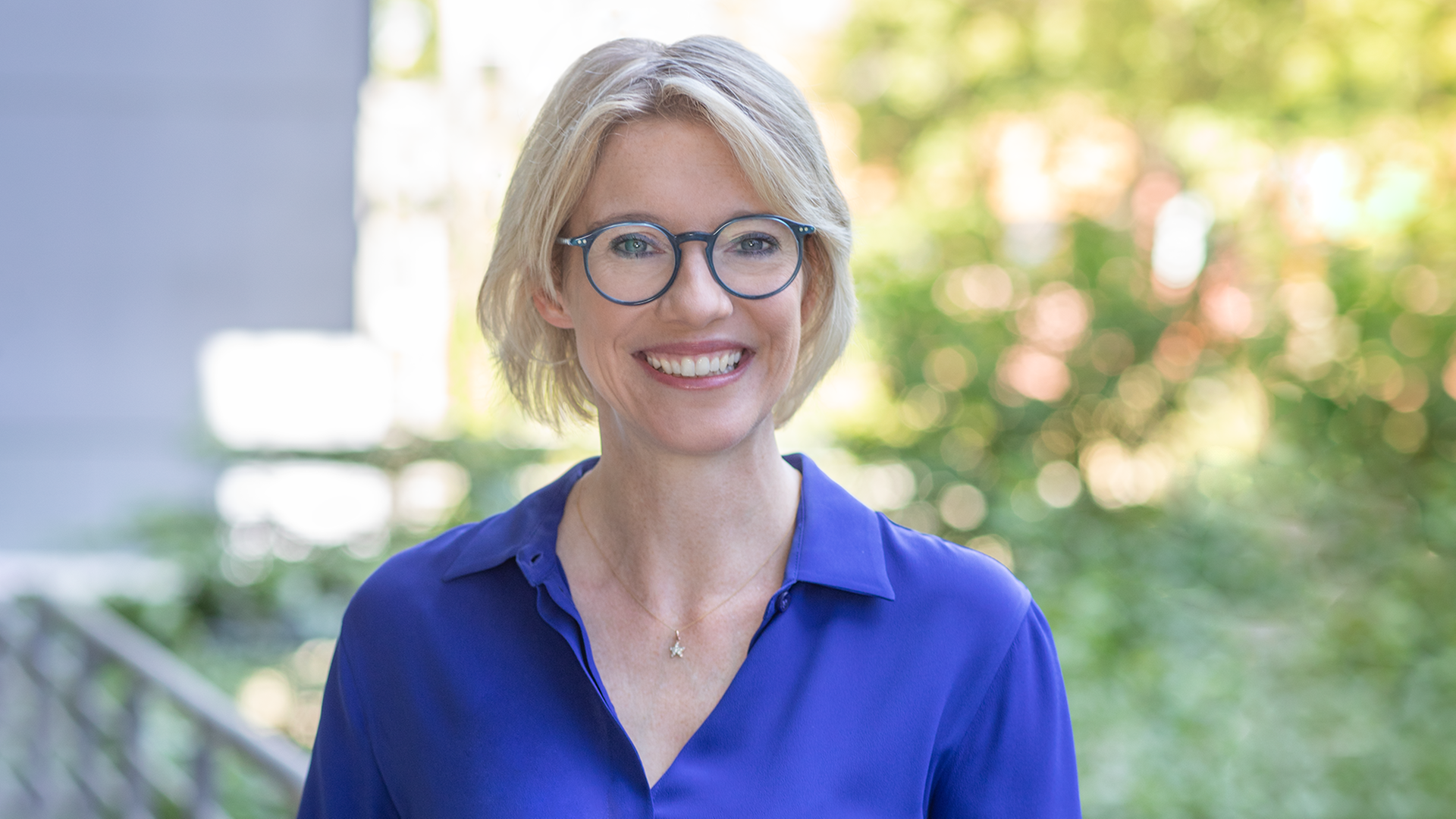 ZDF-Redakteurin Christina von Ungern-Sternberg lächelt für ein Porträtfoto vor grüner Landschaft in die Kamera