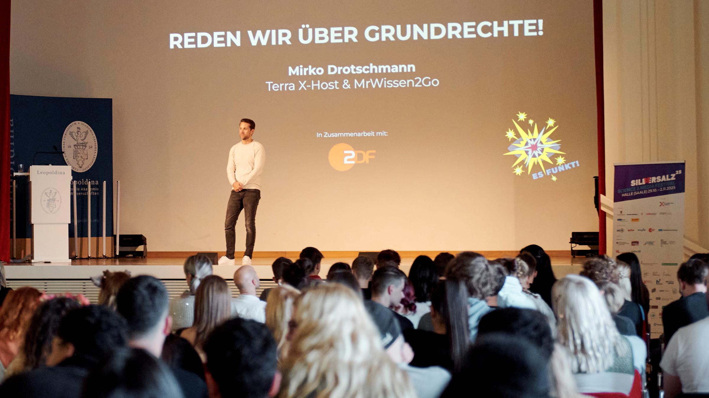 Das ZDF auf dem Silbersalz Festival 25: Mirko Drotschmann auf der Bühne vor einem vollen Zuschauersaal während seines Vortrags im Festsaal der Leopoldina