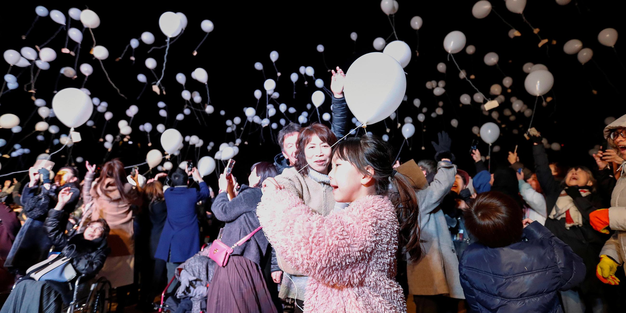 Teilnehmer beim Silvestercountdown in Tokio, Japan, lassen Ballons fliegen.