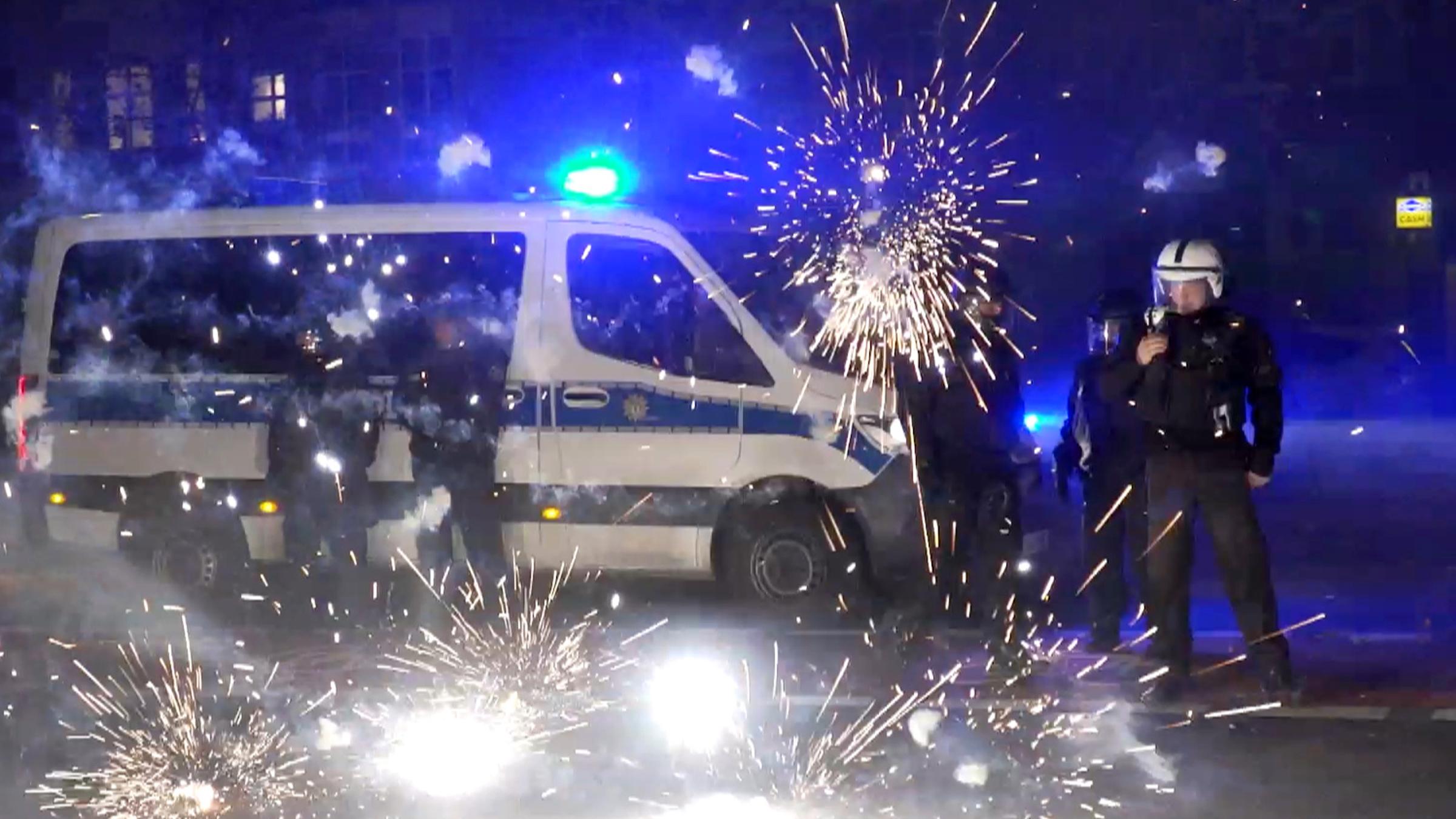 Polizeibeamte stehen hinter explodierendem Feuerwerk am 31.12.2022 in Berlin