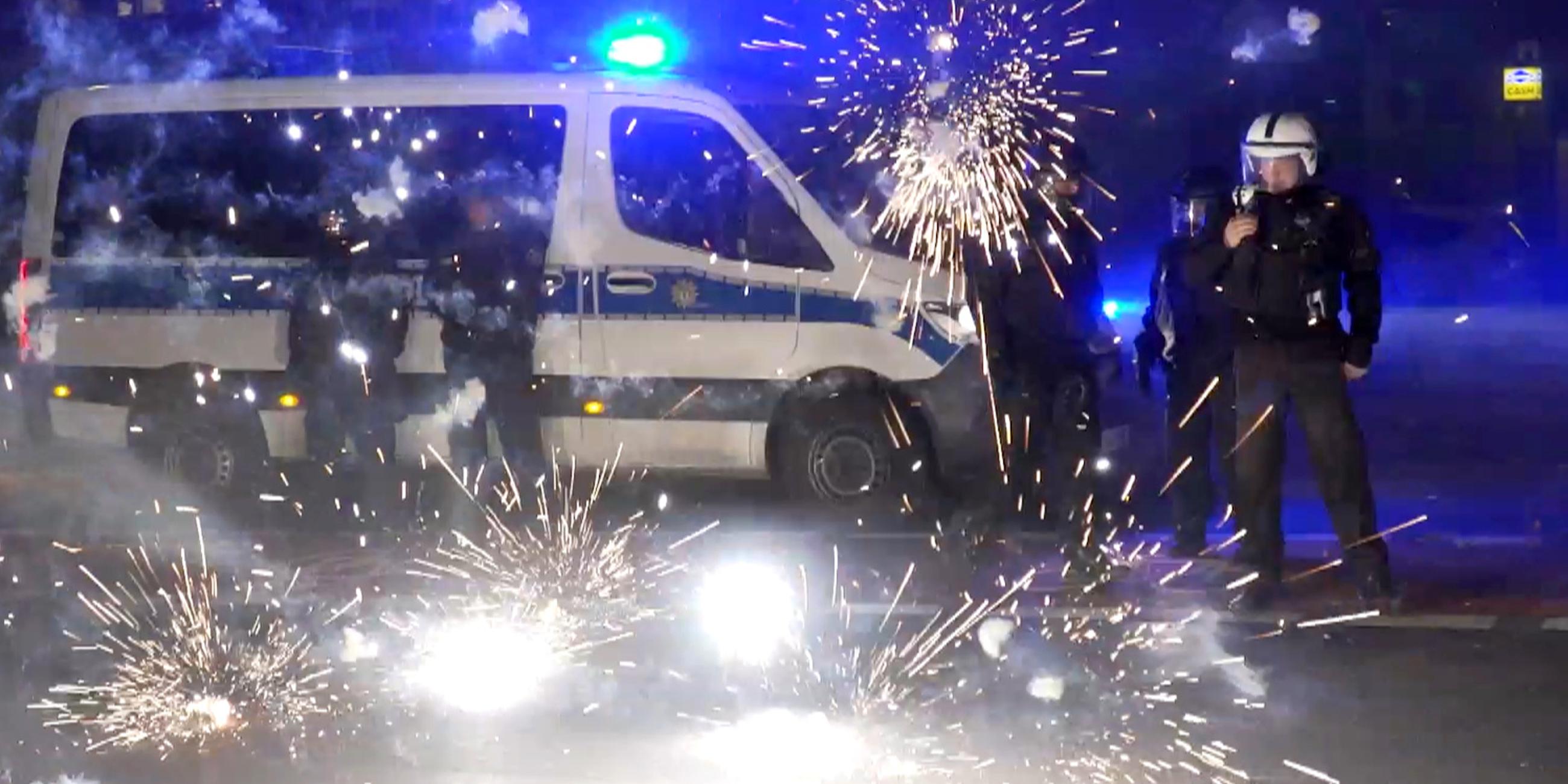 Polizeibeamte stehen hinter explodierendem Feuerwerk am 31.12.2022 in Berlin
