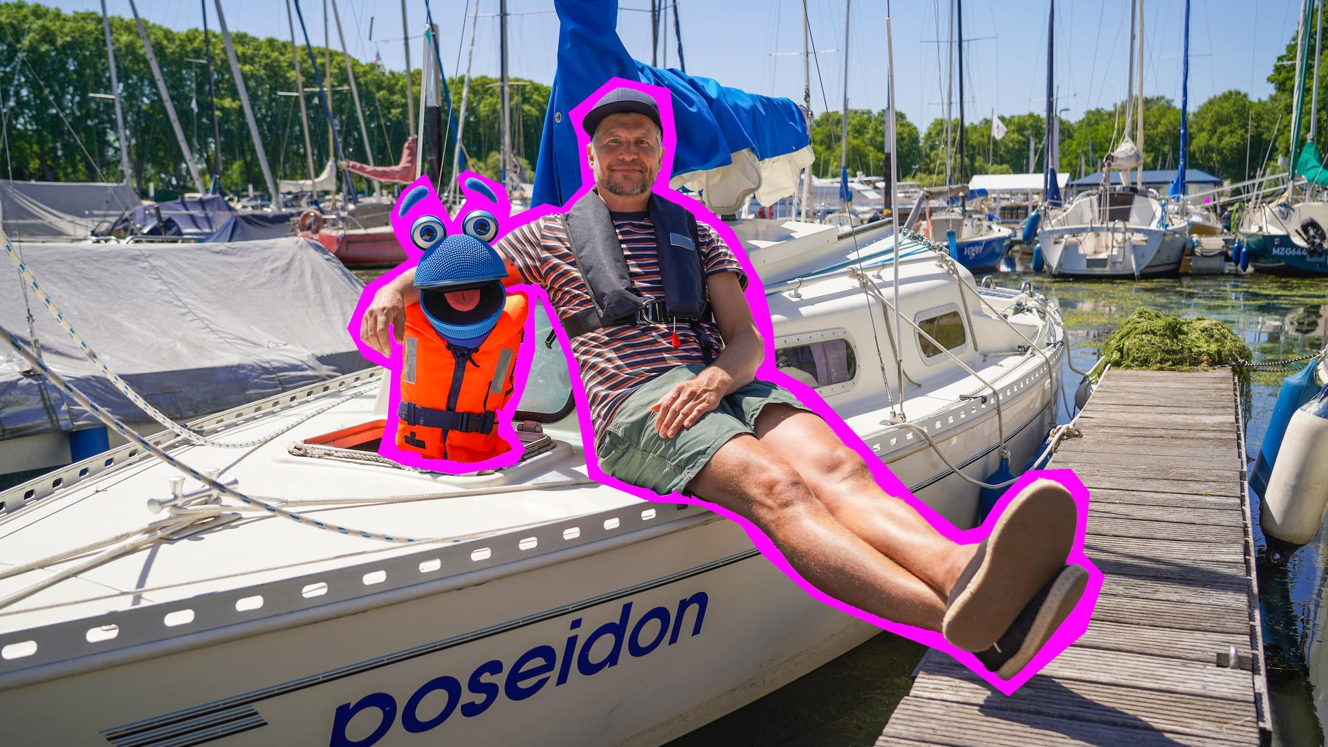 "Singalarm - SingDing auf hoher See": Herr Jan und SingDing sitzen auf einem weißen Segelboot, das an einem Holzsteg in einem Yachthafen angelegt hat. SingDing trägt eine orangefarbene Rettungsweste, Herr Jan hat den Arm um SingDing gelegt und die Beine ausgestreckt.