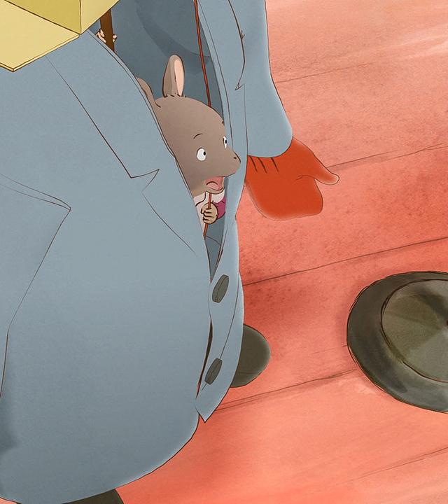 Celestine steckt in einem selbstgebauten Bärenkostüm und singt mit tiefer Stimme als Ernestine die Bärenhymne. Dabei lugt sie aus dem Mantel hervor. Vor ihr steht ein Mikrofon.