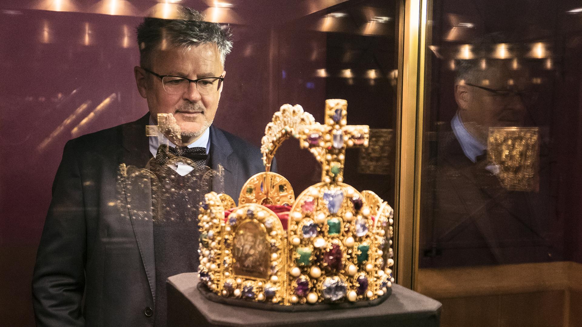 Sir Christopher Clark in der Wiener Schatzkammer. Er betrachtet die Reichskrone des Heiligen Römischen Reiches, die in einer Glasvitrine steht.