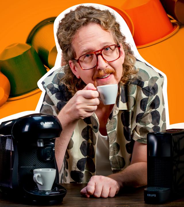 Montage: Uke Bosse steht zwischen den beiden Testgeräten, hält eine Kaffeetasse in der Hand und schaut in die Kamera. Im Hintergrund liegt eine Reihe Kaffeekapseln.