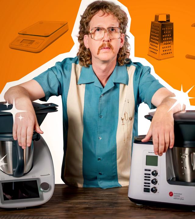 Uke Bosse schaut ernst in die Kamera, seine Arme stützen sich links auf einen Thermomix und rechts auf eine "Monsieur Cuisine"-Maschine.