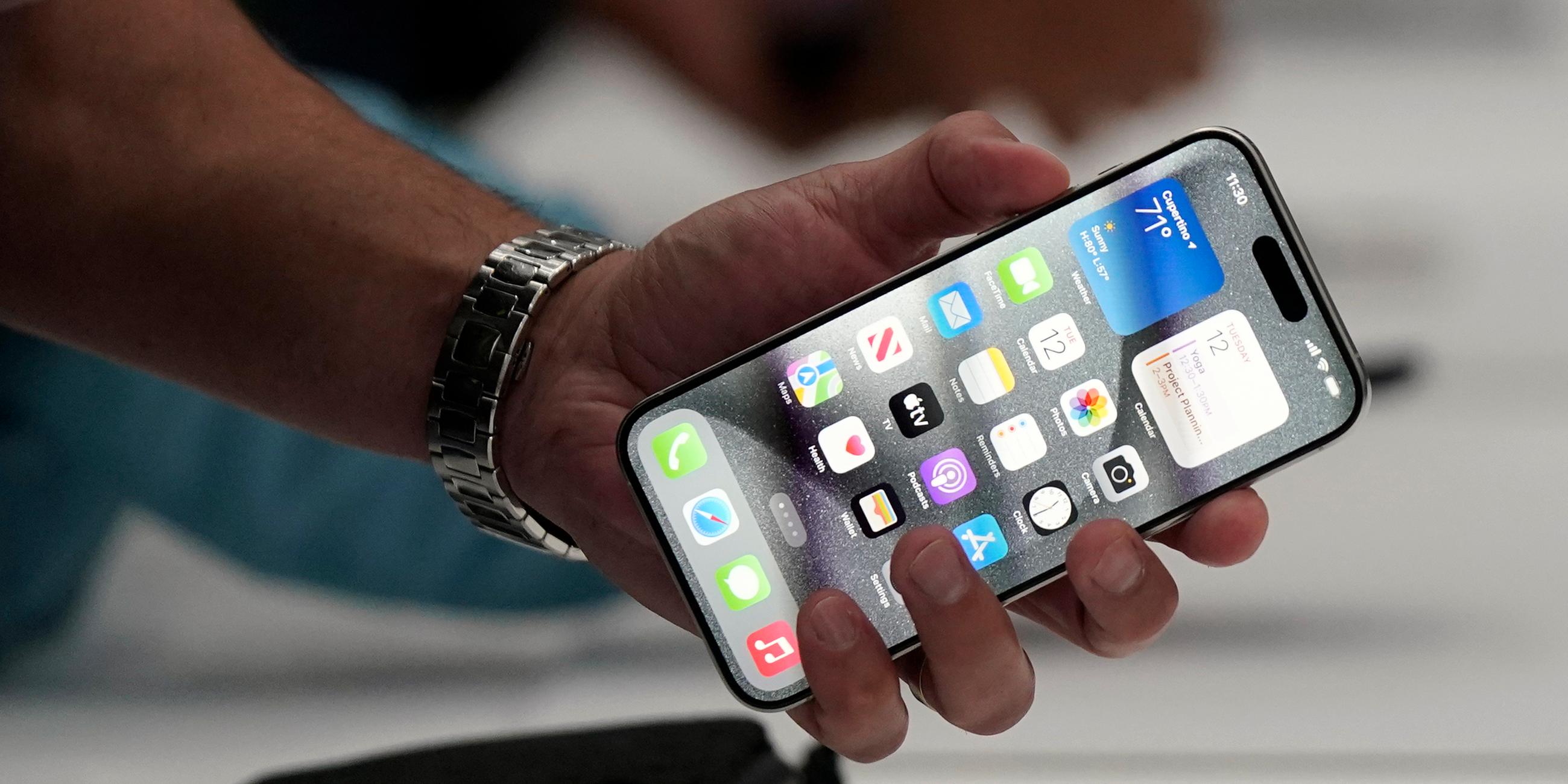 Eine Hand hält ein Iphone mit entsperrtem Bildschirm in der Hand.