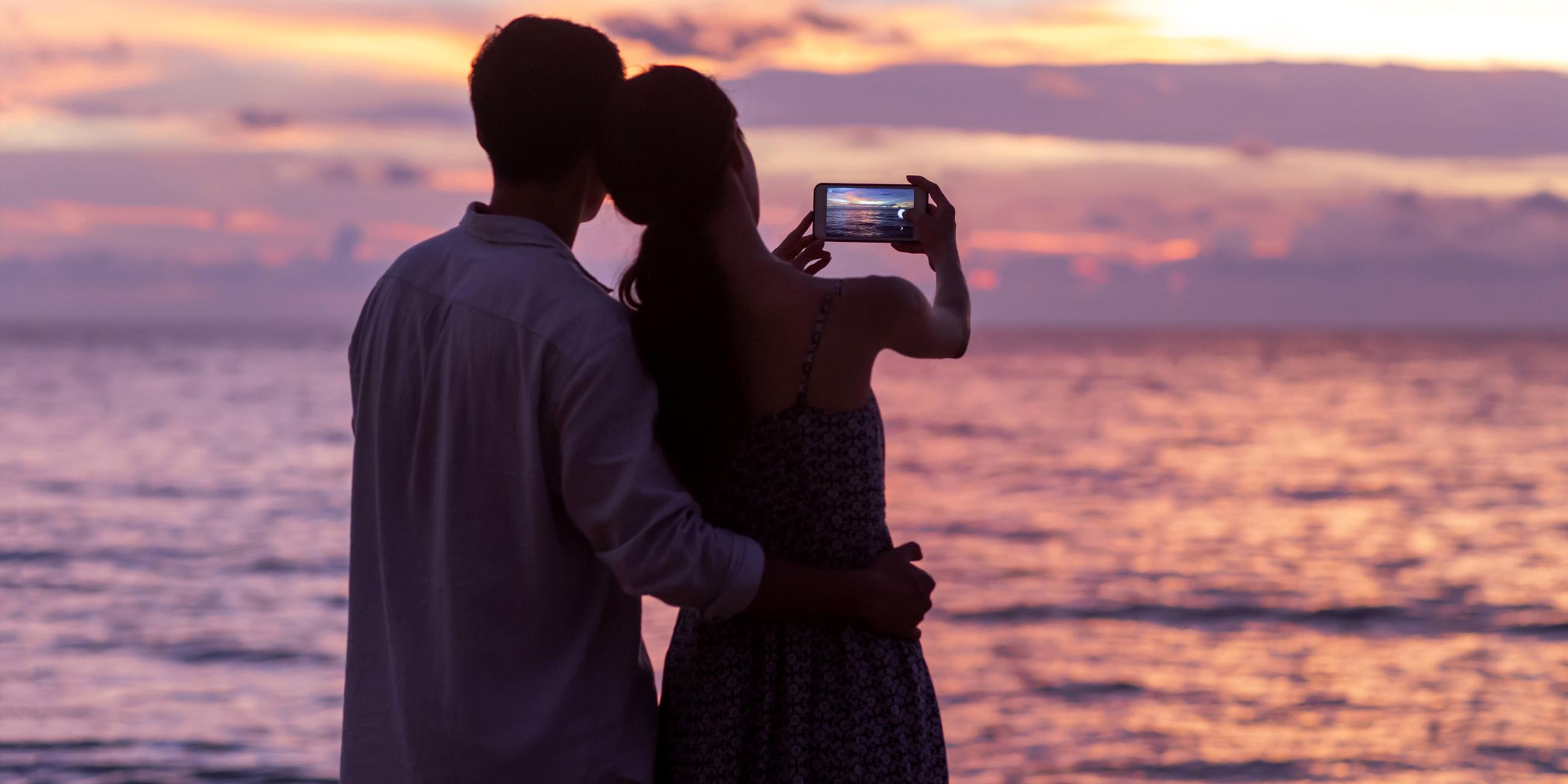 Ein junges Paar mit Smartphone am Strand