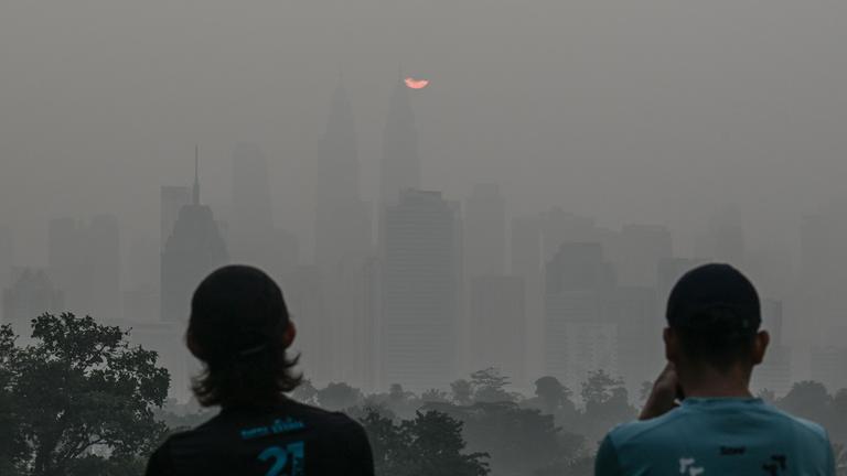 Menschen betrachten am Morgen des 17. Oktober 2026 bei Sonnenaufgang die dunstverhangene Skyline von Kuala Lumpur, während das Land weiterhin in einen Dunst gehüllt ist, der durch Brände in Indonesien verursacht wurde.