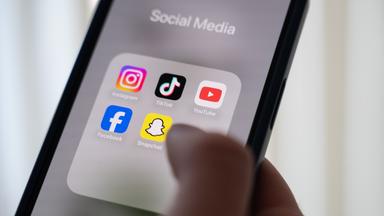 Social Media Apps auf einem Handy, ein Finger tippt auf das Display