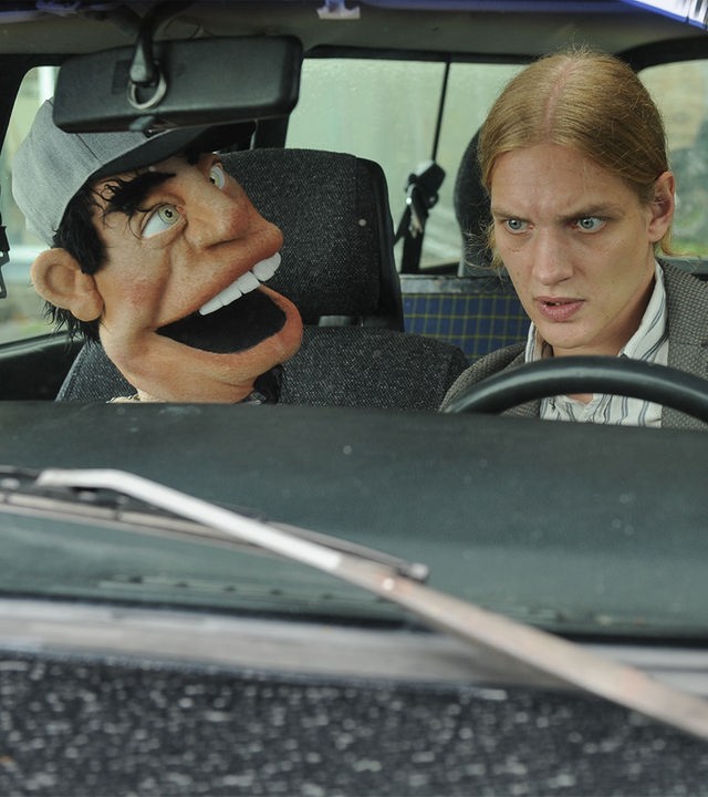 "SOKO Stuttgart - Bauchgefühle": Simon Janetski (Paul Boche) sitzt am Steuer eines Autos. Neben ihm seine Bauchrednerpuppe Herbert.