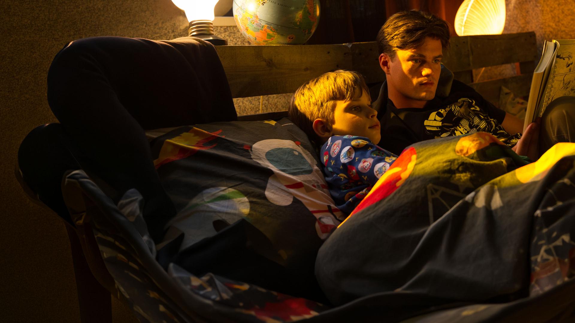 "SOKO Stuttgart - Crashman": Felix Kühn (Yannik Rebmann) liegt mit Toni Kühn (Paul Triller) im Bett und lässt sich von ihm einen Comic vorlesen.