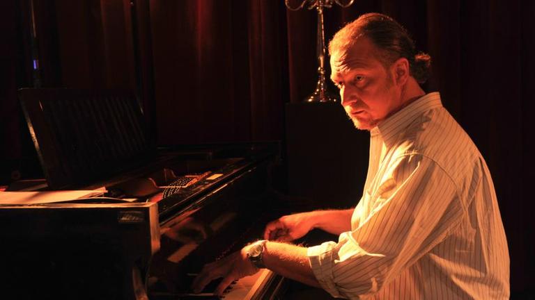 "SOKO Stuttgart - Das Leben des Brian": Ronny Fischbach (Matthias Komm) sitzt bei mattem Licht in der Jazzkneipe an einem Piano.