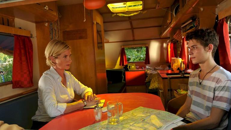 "SOKO Stuttgart - Klassenfahrt in den Tod": Martina Seiffert (Astrid M. Fünderich) sitzt mit dem Schüler Tim Bauer (Julius Forster) zur Befragung in einem Wohnwagen.