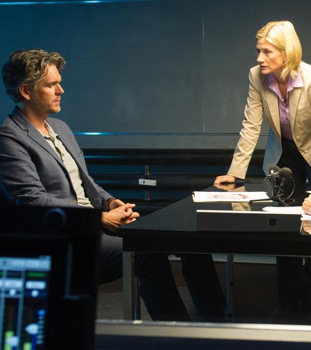Selma Kirsch (Yve Burbach) sitzt vor Moritz Lehnert (Matthias Beier) am Tisch im Vernehmungsraum, während Martina Seiffert (Astrid M. Fünderich) zwischen den beiden auf dem Tisch lehnt. Die Ermittlerinnen setzen Lehnert gehörig zu.