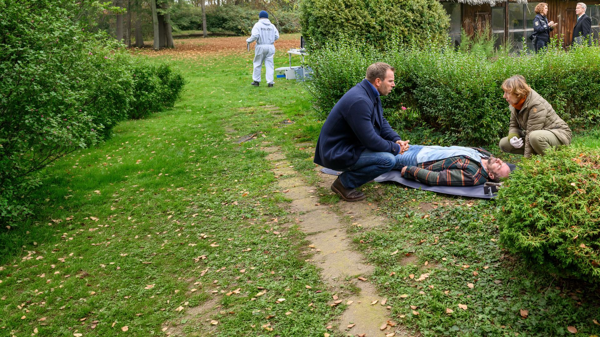 "SOKO Wismar – Der Heimkehrer": Dr. Helene Sturbeck (Katharina Blaschke) und Lars Pöhlmann (Dominic Boeer) knien vor Sven Thalers Leiche (Matijas Versic). Im Hintergrund befragt Paula Moorkampf (Stella Hinrichs) den Makler Hansen (Leif Evers), der den Toten entdeckt hat.