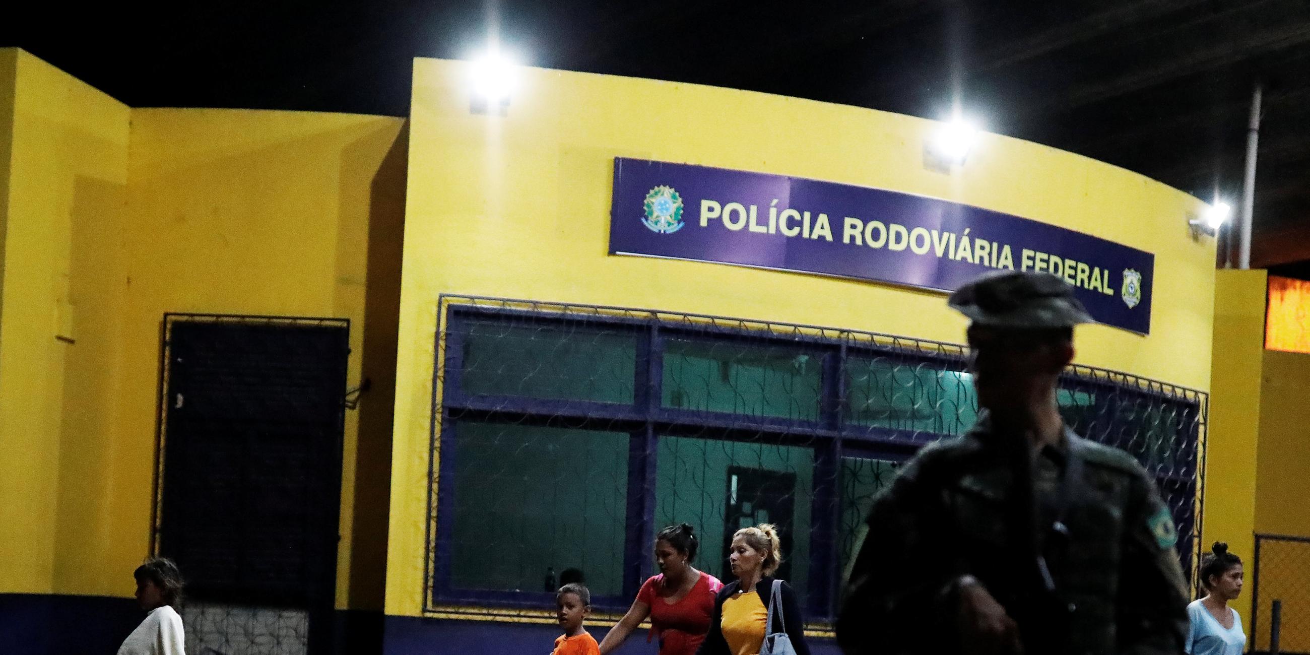 Ein brasilianischer Soldat im Vordergrund, Einwanderer im Hintergrund; 20.08.2018