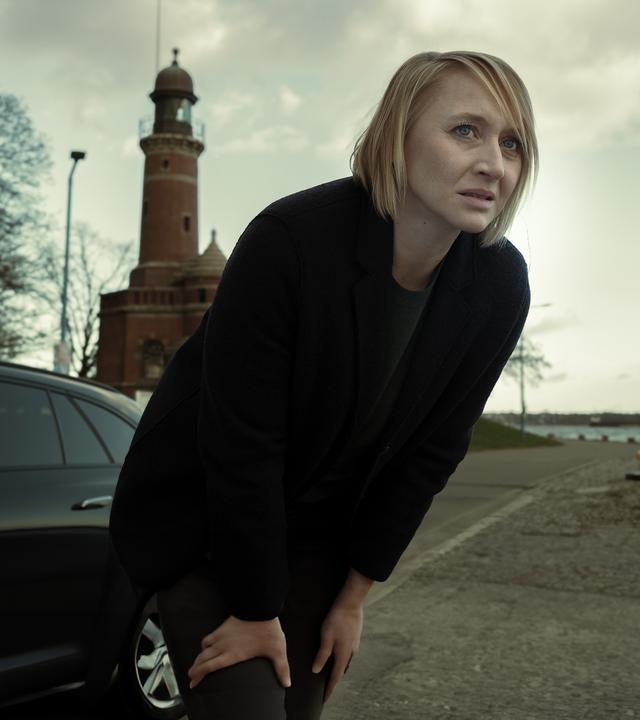 "Solo für Weiss - Blackout": Nora Weiss (Anna Maria Mühe) steht nach vorne gebeugt auf einer Straße am Ufer. 