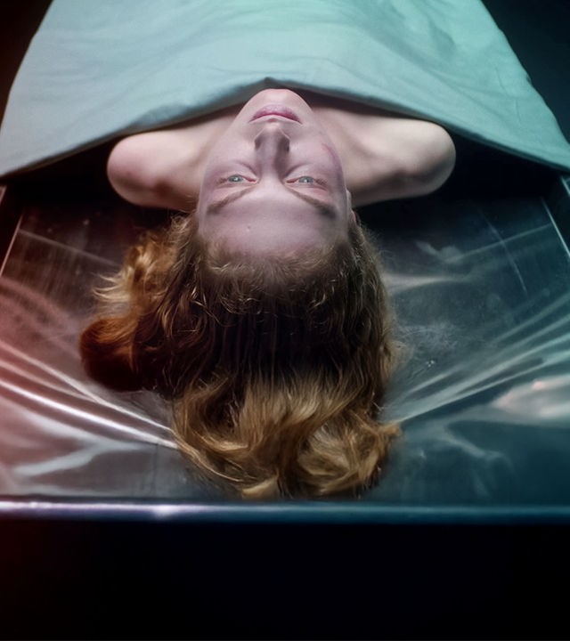 Die Leiche einer Frau liegt auf einem Obduktionstisch. Ihr Kopf und die Schulterpartie ragen unter einem Tuch hervor.